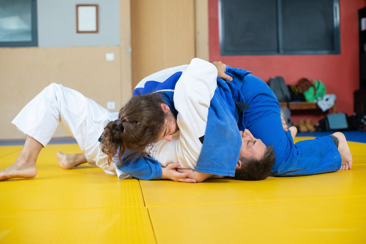 Two judokas practicing grappling techniques indoors during a judo training session.